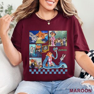Pu&ograve; includere: T-shirt bordeaux con una grafica colorata dei personaggi del film d'animazione Zootropolis. Il design include varie scene e il titolo del film. La maglietta ha un girocollo e maniche corte.
