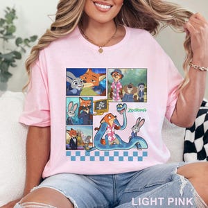 Pu&ograve; includere: T-shirt rosa chiaro con una grafica colorata dei personaggi del film d'animazione Zootropolis. La grafica include pannelli in stile fumetto con immagini dei personaggi e la parola "Zootopia".