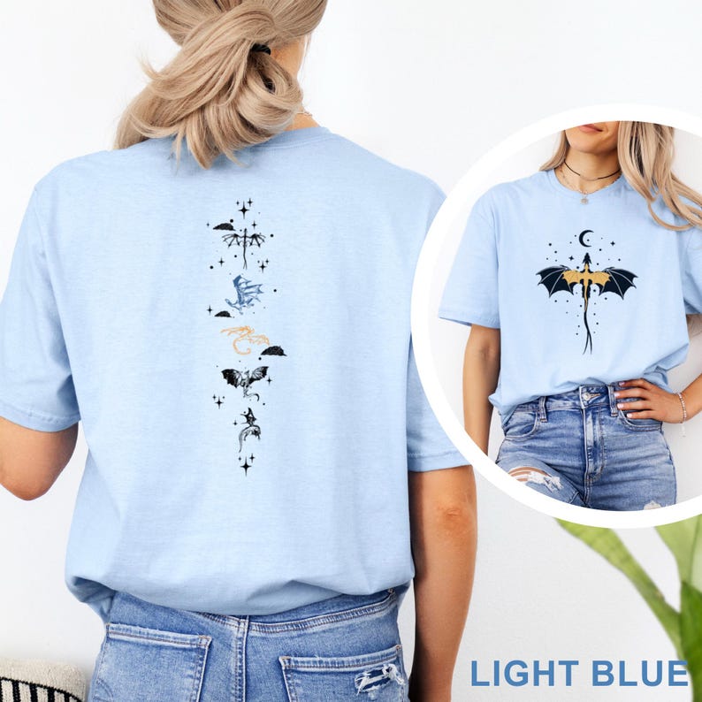 Pu&ograve; includere: T-shirt azzurra con un disegno di drago. La parte posteriore della maglietta presenta una disposizione verticale di illustrazioni di draghi in vari colori. La parte anteriore della maglietta presenta un drago con una luna crescente e stelle. Il testo "LIGHT BLUE" &egrave; in basso.