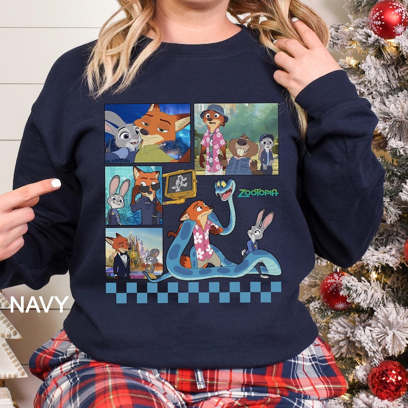 May include: A navy blue long-sleeve sweatshirt featuring a graphic print of various scenes from the movie Zootopia. The design includes multiple panels showing characters like Judy Hopps and Nick Wilde, with the Zootopia logo and a blue checkered border.
