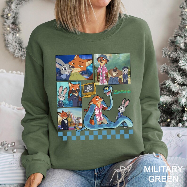 May include: A military green crewneck sweatshirt featuring a graphic print of Zootopia characters including Judy Hopps and Nick Wilde. The design includes multiple panels showing scenes from the movie, a large blue snake, and the Zootopia logo.