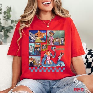 Pu&ograve; includere: T-shirt rossa con una stampa grafica dei personaggi del film d'animazione Zootropolis. Il design presenta una volpe, un coniglio e altri personaggi in stile fumetto. La parola "Zootopia" &egrave; anche visibile.