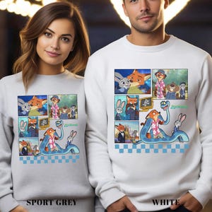 May include: A light grey sweatshirt and a white sweatshirt, each featuring a graphic print of Zootopia characters including Judy Hopps and Nick Wilde in various scenes, with a blue and white checkered pattern along the bottom edge of the print.