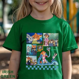 Pu&ograve; includere: T-shirt verde irlandese con una grafica colorata dei personaggi del film d'animazione Zootropolis. La grafica include immagini di una volpe, un coniglio e altri personaggi. Il testo "Zootopia" &egrave; anche visibile.
