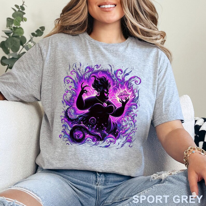 Puede incluir: Camiseta gris deportiva con un gr&aacute;fico de una silueta de un personaje, rodeado de remolinos p&uacute;rpuras y violetas. El personaje sostiene un objeto brillante. El texto "SPORT GREY" est&aacute; impreso en la parte inferior.