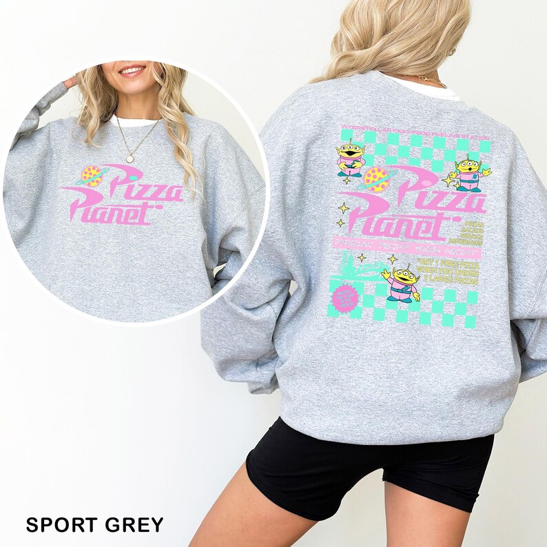 May include: Sport grey sweatshirt featuring the Pizza Planet logo in pink and blue on the front and back. The back design includes cartoon aliens and a checkered pattern. The sweatshirt is a casual, comfortable style.