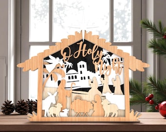 May include: Wooden nativity scene with the words "O Holy Night" cut out. The scene depicts figures of the nativity story, including Mary, Joseph, and baby Jesus, with a star on top. The background is black and white.