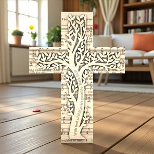 May include: A wooden cross with a tree design cut out of the center. The cross is made from sheet music and has the text "With God all things are possible. Mark 10:27" on the side. The cross is standing on a wooden floor.