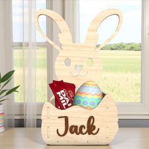 May include: A wooden Easter bunny basket with the name "Jack" on the front. The basket contains red candy packets and a decorated Easter egg. The bunny has cut-out eyes and a heart-shaped nose.