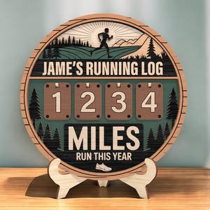 May include: A wooden running log with the text "Jame's Running Log" and "Miles Run This Year." The circular design features a runner silhouette, trees, and the numbers 1, 2, 3, and 4. The log is displayed on a wooden stand.