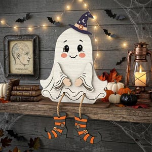 May include: A wooden ghost decoration with a white finish, wearing a dark blue witch hat with a crescent moon and star print. The ghost has dangling legs attached by rope, featuring orange and black striped boots with buckles and patches.