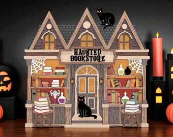 May include: A wooden haunted bookstore decoration with a sign that reads "Haunted Bookstore." The facade features bookshelves, a door, and a black cat. Halloween-themed decor includes pumpkins and candles.
