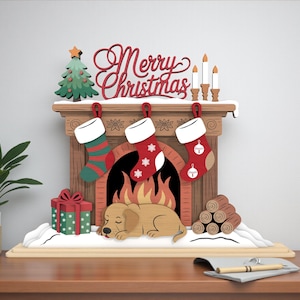 Op de afbeelding: Een houten kersthaardscène met een groene kerstboom, een rood "Merry Christmas" bord en drie hangende kousen. Een slapende hond rust bij een open haard met vuur, een cadeau en houtblokken. De scène staat op een houten basis.