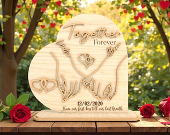 Può includere: Targa in legno a forma di cuore con le parole "Together Forever" e nomi incisi. Presenta mani intrecciate, un cuore e la data 12/02/2020. L'iscrizione recita "From our first kiss till our last breath".
