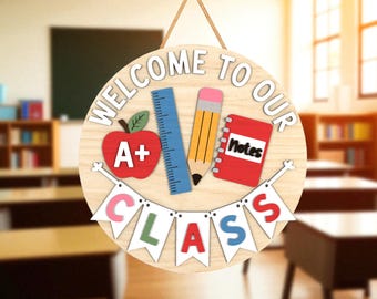 Puede incluir: Letrero de clase de madera con las palabras "Welcome to Our Class". El letrero presenta una manzana roja, una regla azul, un lápiz amarillo y un cuaderno rojo. Una pancarta deletrea "CLASS".