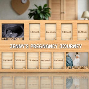 May include: Wooden pregnancy journey photo frame with spaces for monthly photos and a newborn picture. The frame includes the text "MY FIRST SIGHT", "JENNY'S PREGNANCY JOURNEY", and "MY NEWBORN". The frame has spaces for 1st through 9th month photos.