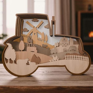 May include: A multi-layered wooden tractor-shaped decoration. The design features a farm scene with a windmill, barn, trees, and animals. The piece is made of various shades of brown wood and sits on a wooden surface.