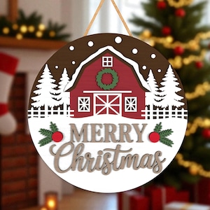 May include: A circular wooden Christmas sign featuring a red barn scene and the words "MERRY Christmas". The sign includes white trees, a green wreath, and a rustic, farmhouse design. It is ready to hang with a natural twine.