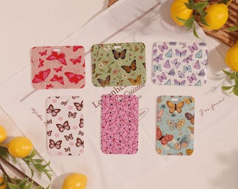 May include: Six rectangular cardholders with butterfly patterns in various colors. Designs include red, green, pink, and blue, with butterflies of different sizes. The cardholders are arranged on a white cloth with lemons and greenery.