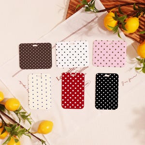 May include: A collection of six rectangular tags with a hole at the top, each featuring a polka dot pattern. The tags come in various colors, including brown, white, pink, cream, red, and black. Lemons and greenery are in the background.