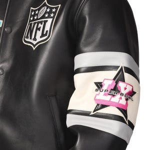 Pu&ograve; includere: Giacca in pelle nera con la toppa del logo NFL sul petto. La manica presenta una toppa Super Bowl LX con un design a stella, dettagli bianchi, grigi e rosa. La giacca ha un classico stile college.
