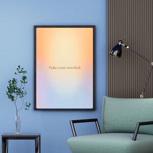 Könnte beinhalten: Innenraum mit einem gerahmten Kunstwerk mit der Aufschrift "Make your own luck". Ein türkisfarbener Sessel mit schwarzen Armlehnen steht neben einer schwarzen Lampe. Ein kleiner Beistelltisch trägt eine Vase mit Grün. Ein grauer Teppich liegt auf dem Boden.