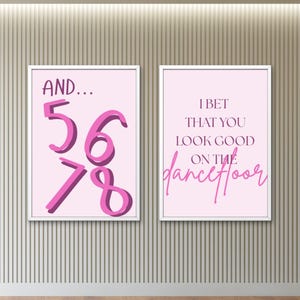 Könnte beinhalten: Zwei gerahmte Kunstdrucke mit rosa Hintergründen. Einer zeigt "AND... 5678" in dunkler rosa Schrift. Der andere zeigt "I BET THAT YOU LOOK GOOD ON THE dancefloor" in dunkler rosa Schrift. Die Rahmen sind weiß.
