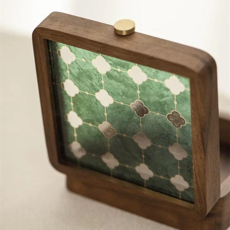 May include: A wooden jewelry box with a hinged lid and a brass knob. The interior features a green patterned design with white, gray, and brown clover-shaped accents. The box is made of dark wood.