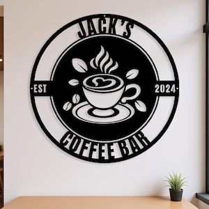 Peut inclure: Panneau métallique noir et blanc pour un café. Le panneau rond porte les mots "Jack's Coffee Bar" et "Est 2024". Une tasse à café avec un motif en forme de cœur est au centre.