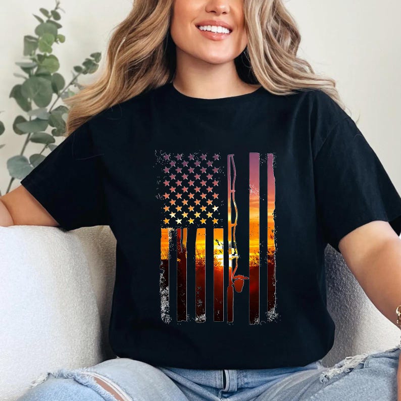 A woman wearing a black t-shirt with an American flag design and a fishing rod graphic, smiling at the camera.