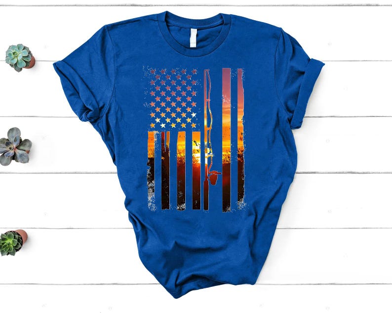 A blue t-shirt with a graphic design depicting an American flag and a sunset landscape.