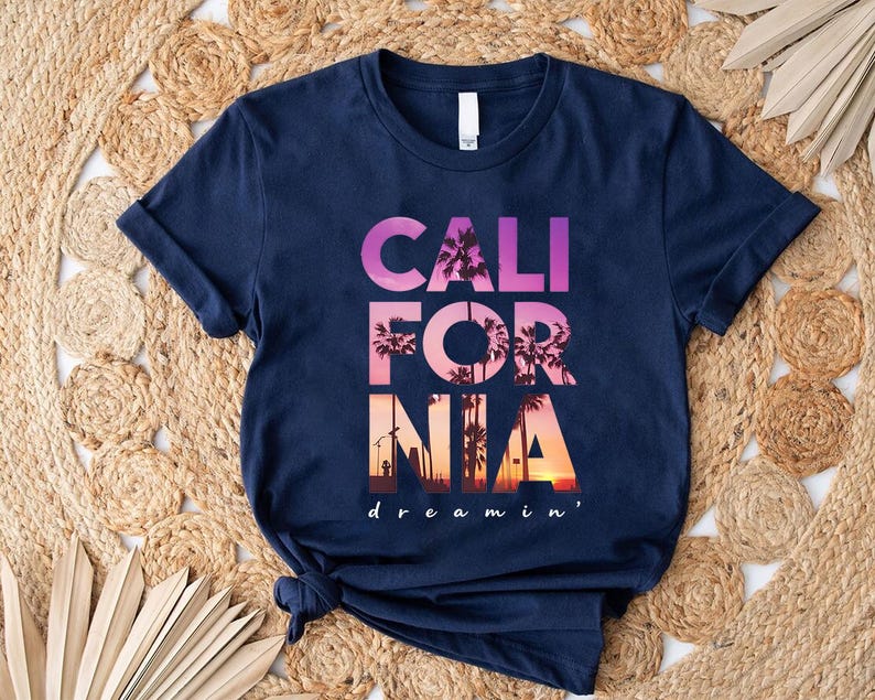 A navy blue t-shirt with the text "CALIFORNIA dreamin'" printed on it, along with a graphic of palm trees and a sunset.