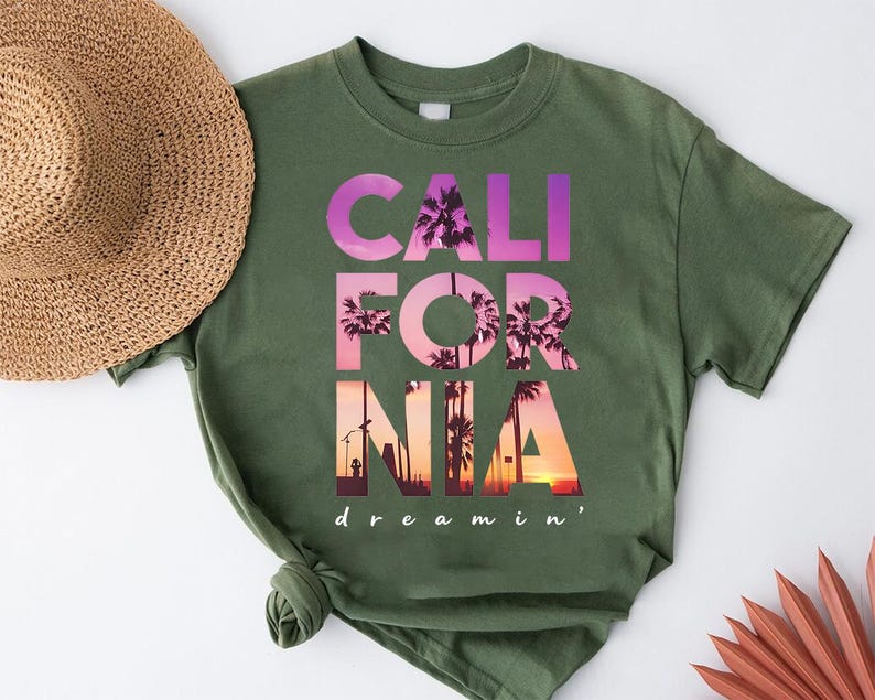 A green t-shirt with the text "CALI FOR NIA" printed on it, along with a straw hat and some decorative items.