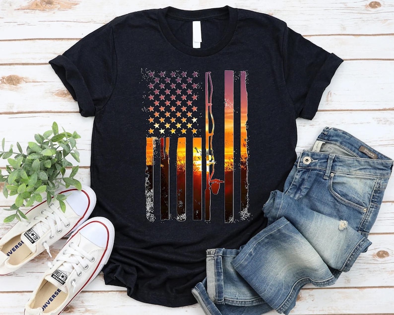 a black t-shirt with a graphic design depicting an American flag and a sunset, along with a pair of jeans and white sneakers.