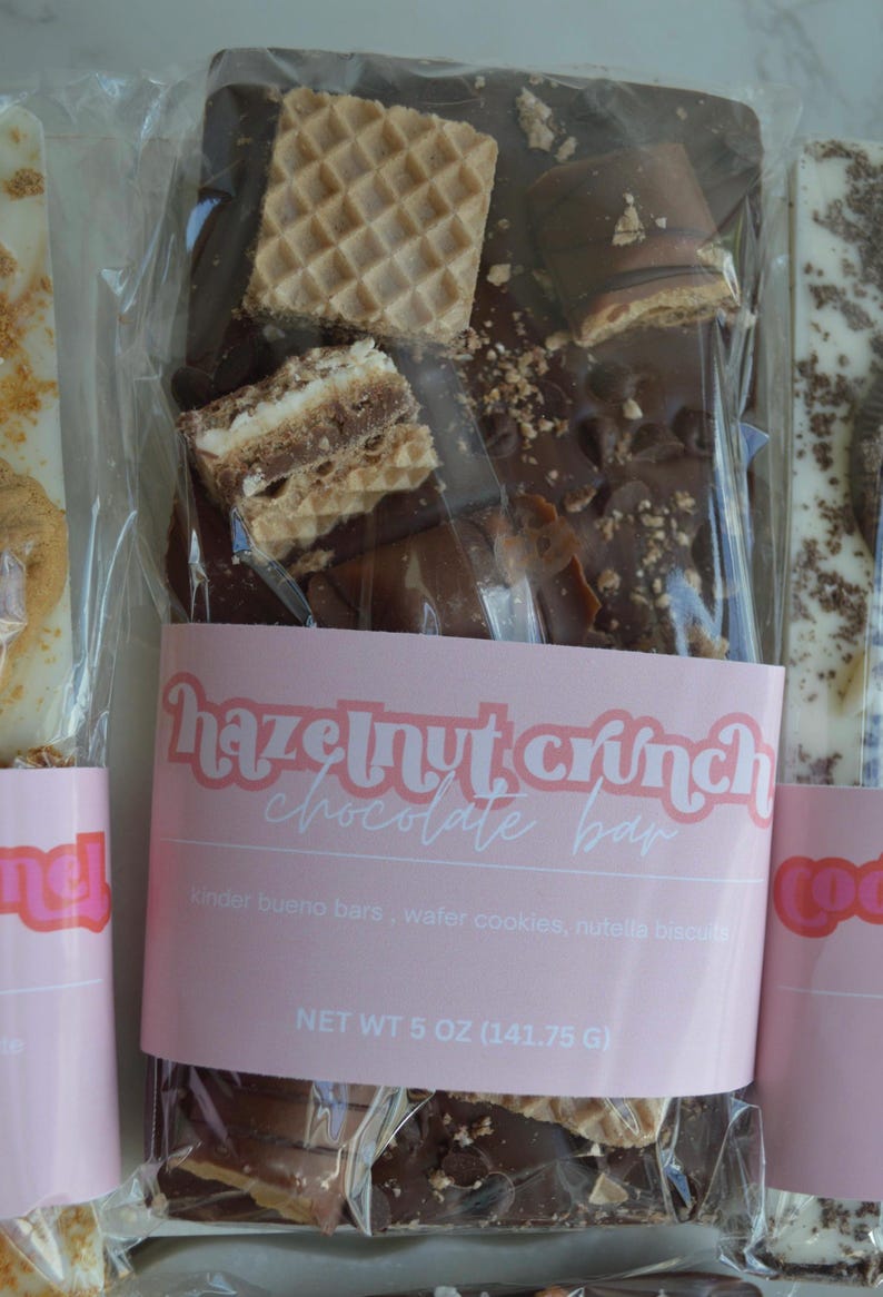 Peut inclure: Une barre de chocolat au croquant de noisettes, avec des barres Kinder Bueno, des gaufrettes et des biscuits Nutella. L'emballage transparent porte une &eacute;tiquette rose avec "Hazelnut Crunch Chocolate Bar". Poids net 141,75 g.