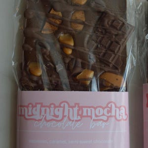 Peut inclure: Une barre de chocolat noir avec des morceaux de caramel et des morceaux de chocolat, emball&eacute;e dans du plastique transparent. La barre est &eacute;tiquet&eacute;e "midnight mocha chocolate bar" avec les ingr&eacute;dients espresso, caramel et chocolat mi-sucr&eacute;. Poids net 141,75 g.