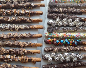 Peut inclure: Rangées de bâtonnets de bretzels enrobés de chocolat avec diverses garnitures. Certains sont recouverts de chocolat noir et garnis de noix, de tasses de beurre de cacahuète et de caramel. D'autres sont décorés de vermicelles, de bonbons et de guimauves.