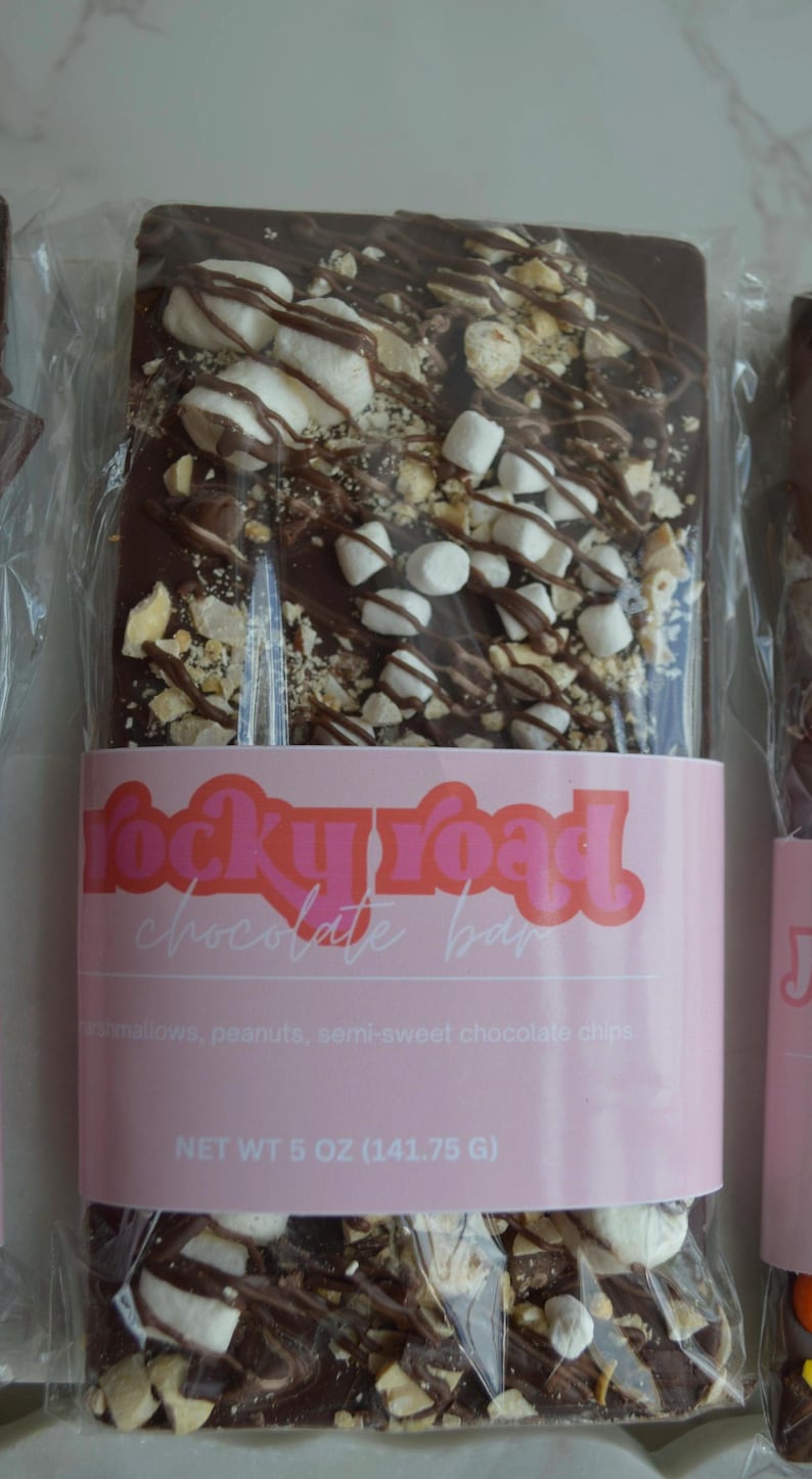 Peut inclure: Barre de chocolat noir Rocky Road avec guimauves, cacahu&egrave;tes et p&eacute;pites de chocolat mi-sucr&eacute;. Emball&eacute; dans du plastique transparent avec une &eacute;tiquette rose &laquo; rocky road chocolate bar &raquo;. Poids net 141,75 g.