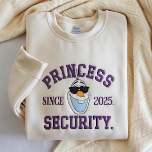 以下が含まれることがあります： 紫色の「PRINCESS SINCE 2025 SECURITY」の文字とサングラスをかけた漫画の雪だるまが描かれた、クリーム色のスウェットシャツ。クルーネックと長袖です。