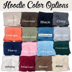 May include: An image showcasing a variety of hoodie color options. The image displays folded hoodies in various colors, including sand, chocolate, black, grey, orange, military green, Carolina blue, sport grey, navy, light pink, light blue, forest green, white, maroon, brow, and beige. The text "Hoodie Color Options" is at the top.