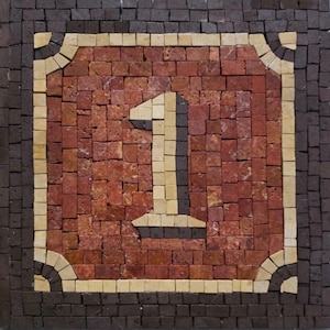 May include: A mosaic tile artwork featuring the number "1". The number is in a light beige color, set against a background of red-brown tiles. The mosaic is framed by a dark brown border with beige corner accents.