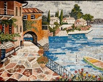 Puede incluir: Una obra de arte en mosaico que representa una escena costera con edificios, un arco y agua. Los edificios son de tonos naranja y marrón, con un camino adoquinado que conduce al agua. Un pequeño bote verde y amarillo flota en el agua.