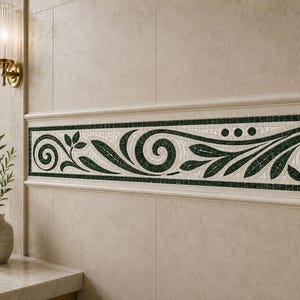 May include: A bathroom wall features a decorative mosaic border with a dark green and white floral design. The border is framed by a light beige molding, and the wall is tiled in a matching beige color. A gold-toned faucet and mirror are visible.
