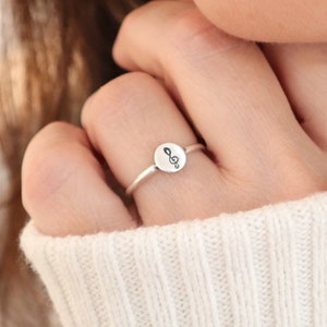 May include: A silver ring with a small round charm featuring a treble clef symbol.