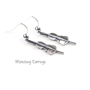 May include: A pair of silver dangle earrings featuring a cello design. Matching Earrings.