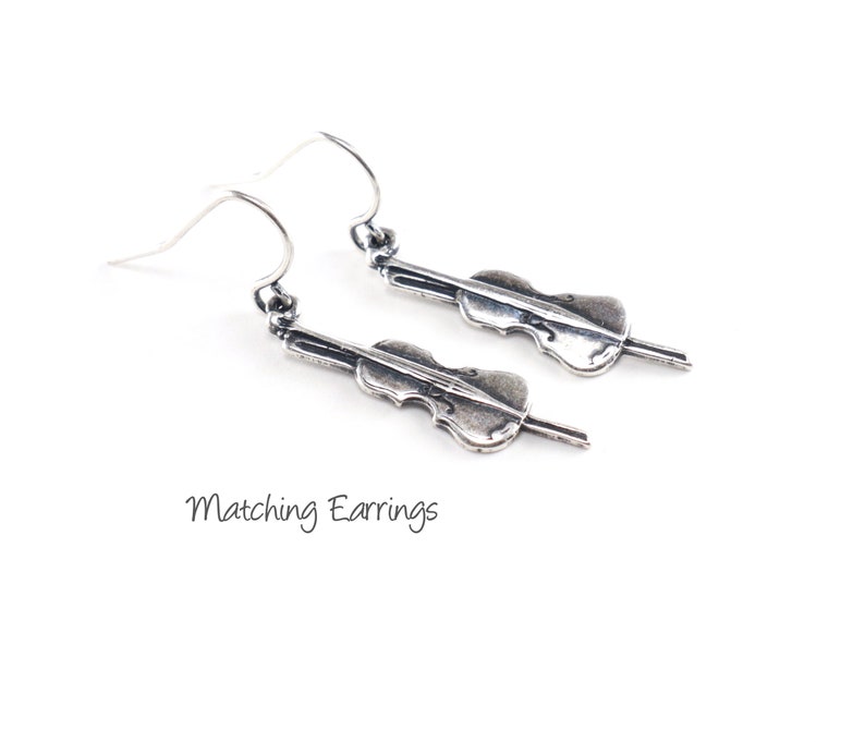 May include: A pair of silver dangle earrings featuring a cello design. Matching Earrings.