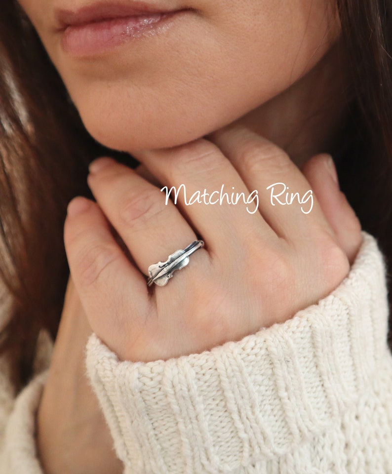 May include: A silver ring with a leaf design. The ring is worn on a person's finger. The text "Matching Ring" is written on the image.