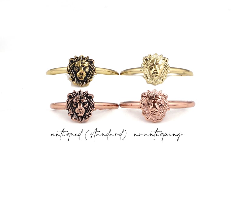 May include: Two gold lion head rings, one with an antiqued finish and one with a standard finish. The rings are shown side-by-side.