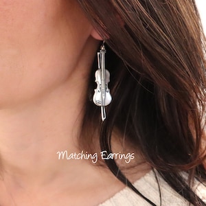 May include: Silver violin-shaped dangle earrings. Matching Earrings.