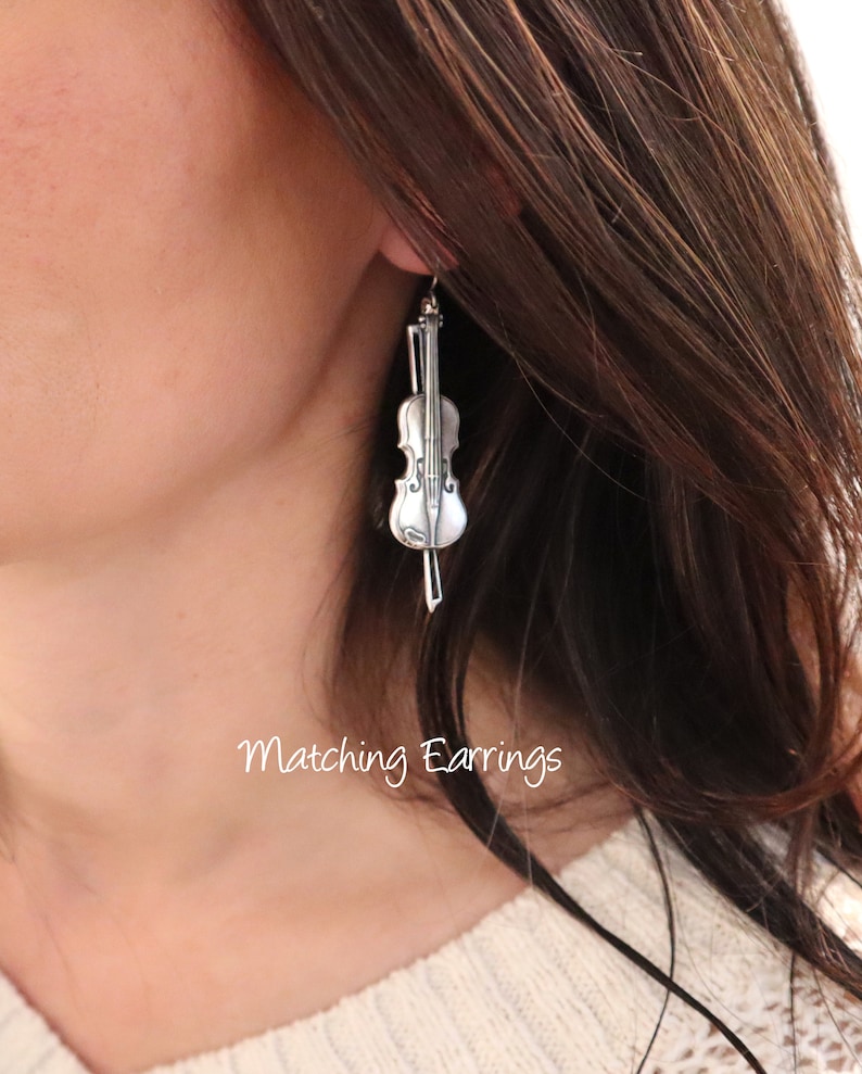 May include: Silver violin-shaped dangle earrings. Matching Earrings.